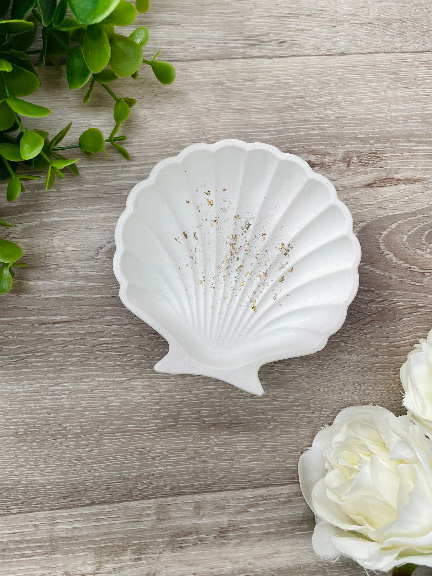 Clam shell bowl ✨  Natural white with gold leaf flakes  Approx size 95mm x 180mm (9.5cm x 18cm)  Unlike our epoxy resin products, this beauty is made out of eco resin with a more natural, rustic final finish.  This is a great sized to use as a catchall for jewellery or hair accessories!  Handmade in Waikato, New Zealand.