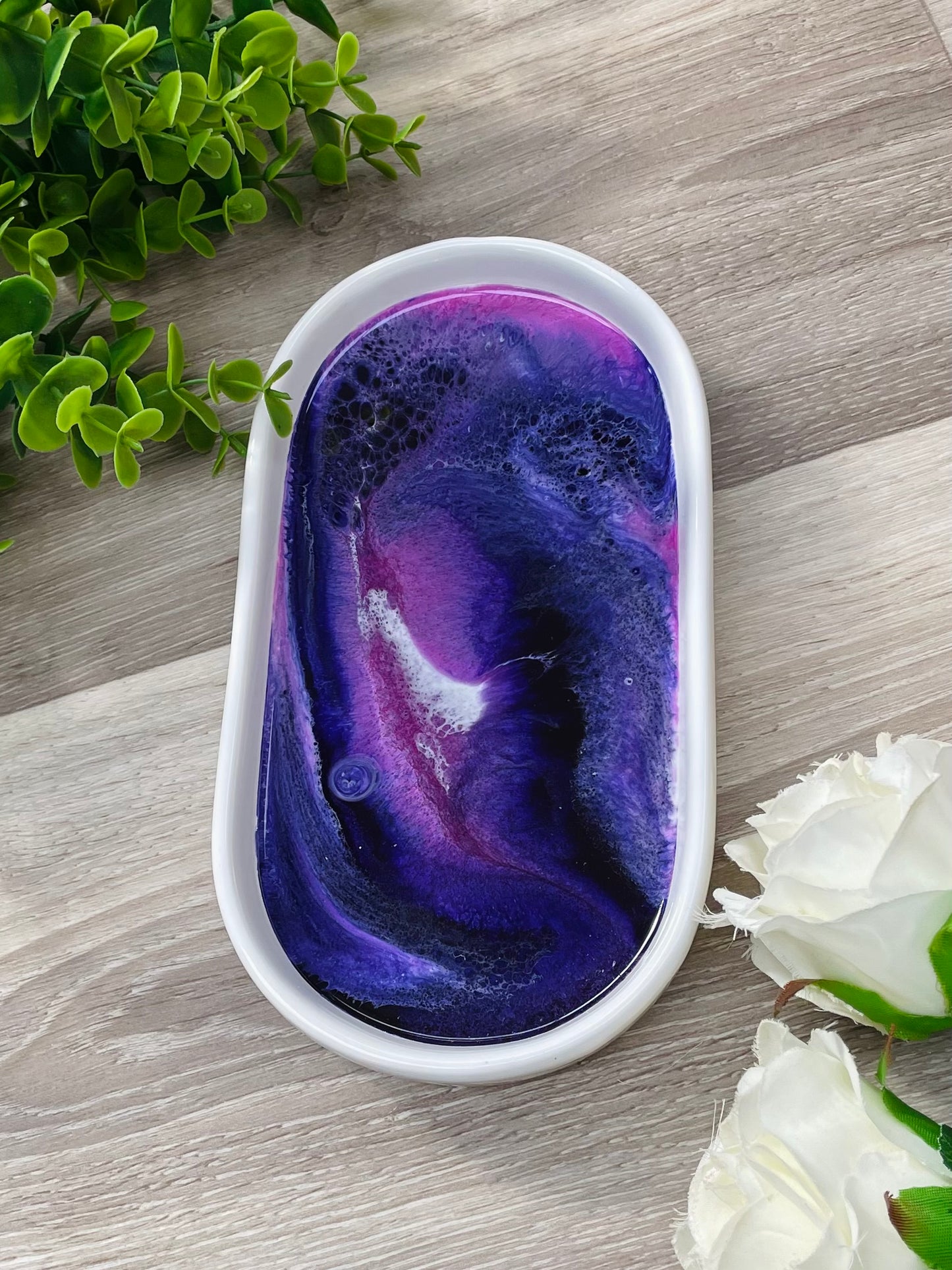 Oval Shaped Ceramic Trinket Tray  Gorgeous deep violet purple tones with pops of vivid purple & white 💜💫  Depending on the angle you look at the tray, you will always see something different!  Approx size 110mm x 200mm (11cm x 20cm)  This is a great size as a catchall for keys & pens or use as a décor item in the bathroom or living area. You can also use these on your vanity for perfume bottles, creams, sprays etc.  Last photo shows an example of use  Note: Some trays have minor factory imperfections